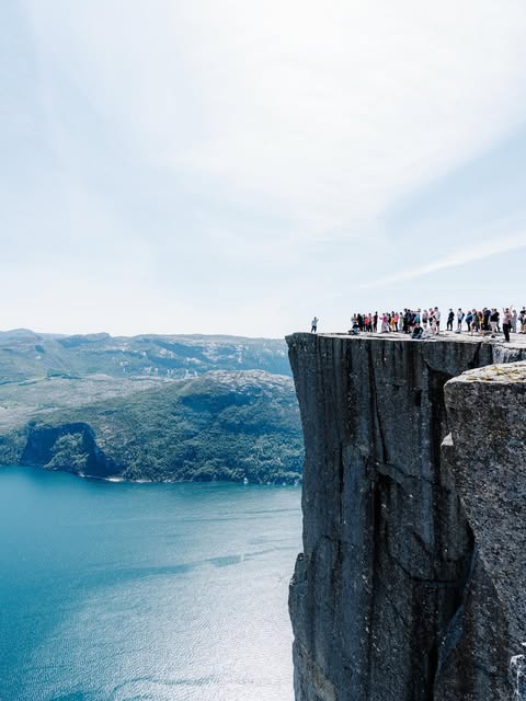 Visitors on a cliff above a Norwegian fjord